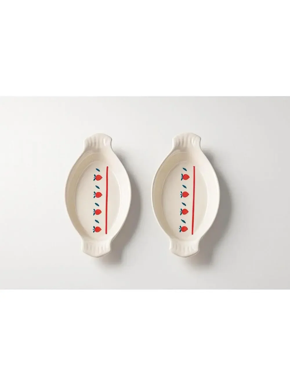 White ceramic oval au gratin dish with red apple and green leaf decoration.